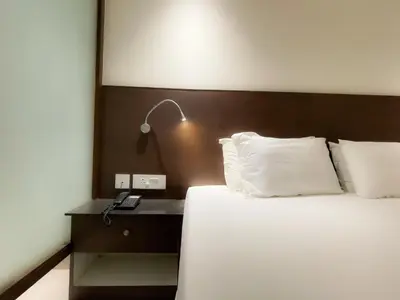 a bed in a hotel room with a lamp on a table at SV Grand in Mettuppālaiyam