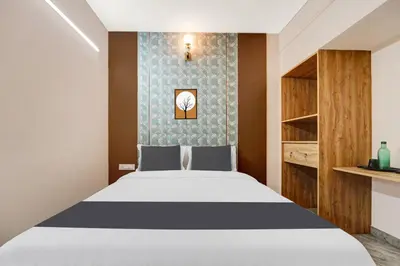 a bedroom with a white bed and a wall at Super Hotel O Vilankurichi in Coimbatore