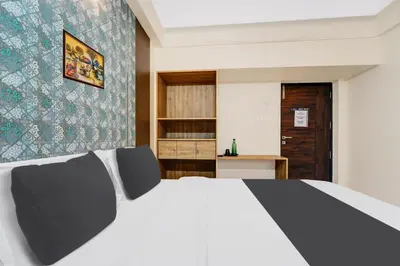 a bedroom with a white bed with two chairs at Super Hotel O Vilankurichi in Coimbatore