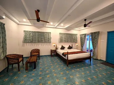 a bedroom with a bed and a table and chairs at Ibex Resorts, Coimbatore Kakarla in Alāndurai