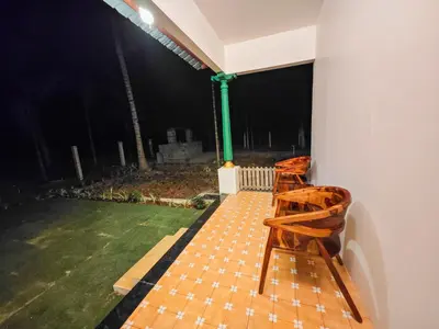 two wooden chairs sitting on a patio at night at Ibex Resorts, Coimbatore Kakarla in Alāndurai