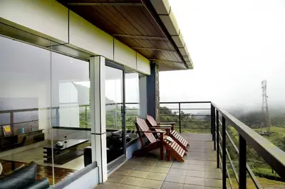 a balcony of a building with a table and benches at Ibex Resorts, Valparai Tale Rock in Vālpārai
