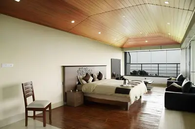 a bedroom with a large bed with a wooden ceiling at Ibex Resorts, Valparai Tale Rock in Vālpārai
