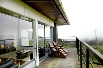 a balcony of a building with a table and benches at Ibex Resorts, Valparai Tale Rock in Vālpārai