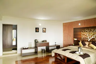 a bedroom with a large bed with a tree on the wall at Ibex Resorts, Valparai Tale Rock in Vālpārai