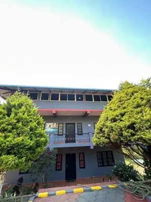 a building with a balcony and two trees at Mountain View Villas in Madikeri