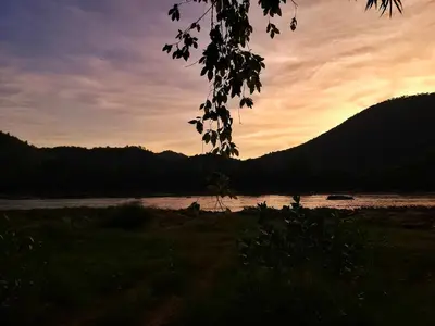 a sunset over a river with mountains in the background at Gypsy habitat Backpackers Space in Wodapatti