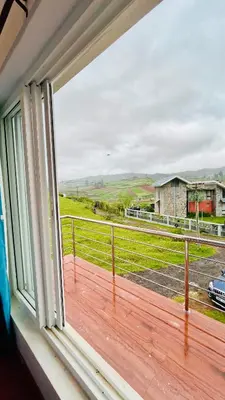 a window with a view of a field at Away From Home - 6 - Home Stay Ooty, Entire 3BHK Villa in Ooty