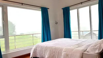 a bedroom with a bed and two large windows at Away From Home - 6 - Home Stay Ooty, Entire 3BHK Villa in Ooty