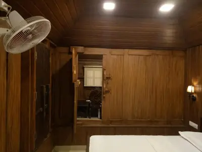 a bedroom with wood paneling and a window and a fan at Sparrow Vale Resort in Kotamangalam