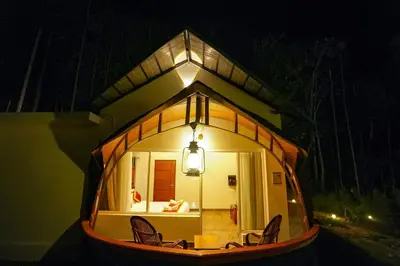 a small house with chairs in the night at Ginberry Holidays in Wayanad