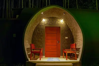 a circular room with two chairs and a wooden door at Ginberry Holidays in Wayanad