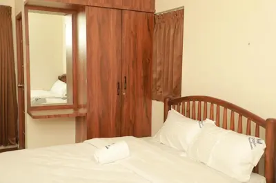 a bed with a wooden headboard and a mirror at Nilgiri Woodlands Luxury Service Apartments in Mysore