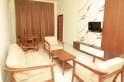 a living room with white furniture and a tv at Nilgiri Woodlands Luxury Service Apartments in Mysore