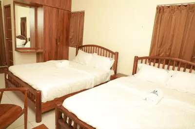 two beds in a room with white sheets at Nilgiri Woodlands Luxury Service Apartments in Mysore