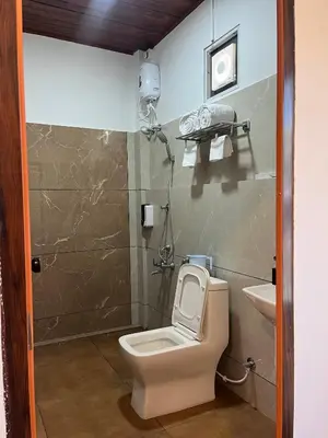 a bathroom with a toilet and a sink at Rivana Homestay in Kushālnagar
