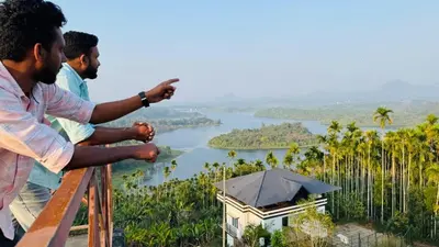 two men sitting on a railing looking out over a lake at mountain lake view private pool villa -Wayanad in Meppādi