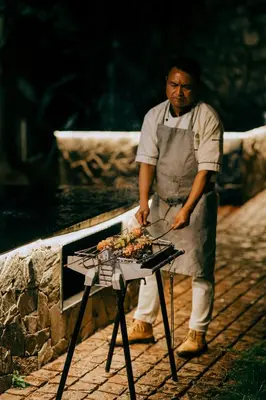 a man is cooking food on a grill at Green Nest Resort Ooty in Kotagiri