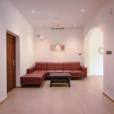 a living room with a red couch and a table at Ohstayz Villa De Estate 64 in Kizhake Chālakudi