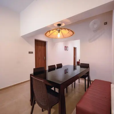 a dining room with a black table and chairs at Ohstayz Villa De Estate 64 in Kizhake Chālakudi