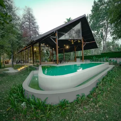 a building with a swimming pool in the grass at Ohstayz Villa De Estate 64 in Kizhake Chālakudi