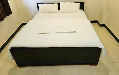 a large bed with a white sheets and a metalatch on it at Rodas Serviced Apartment in Coimbatore