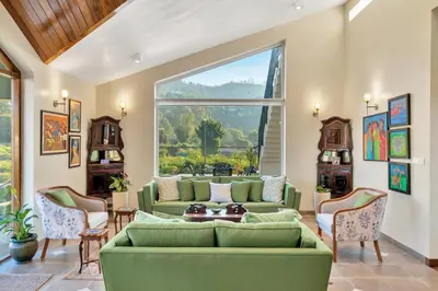 a living room with a green couch and a large window at SaffronStays Coonoor Canvas in Coonoor