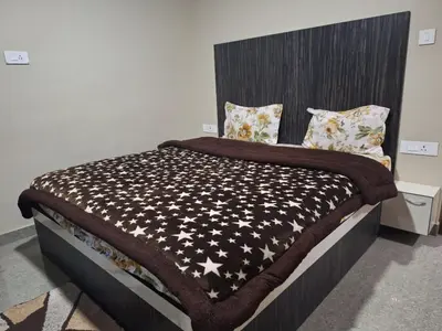 a bedroom with a bed with a black and white comforter at Golden Gate Luxury Villas by LexStays in Ooty