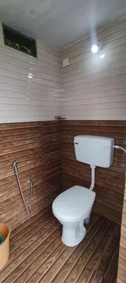a bathroom with a white toilet in a room at Mount Camp in Marayoor
