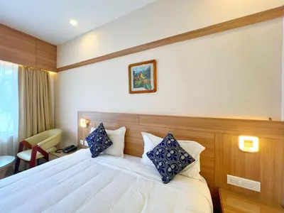 a hotel room with a bed with blue and white pillows at Hotel Amaravathi BY D2V in Manattala