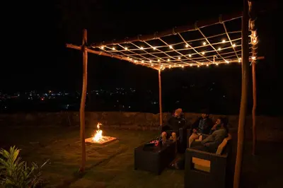 a group of people sitting under a pergola at night at Sliceinn Escapes Pushpanjali - Madikeri, Coorg in Madikeri