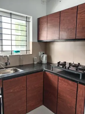 a kitchen with wooden cabinets and a sink at Fully furnished 3BHK 2 Floor Villa in Angamali