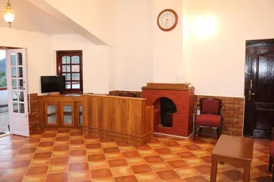 a living room with a fireplace and a clock on the wall at Jennings Abode Doddabetta in Ooty