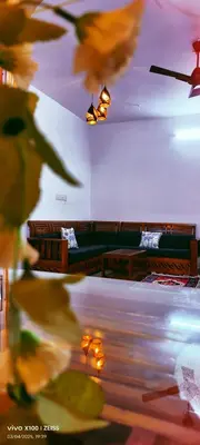 a room with tables and chairs and lights at The Bulbul Nest Homestay in Gūdalūr