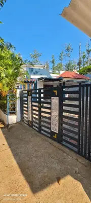 a black gate with signs on the side of a building at The Bulbul Nest Homestay in Gūdalūr