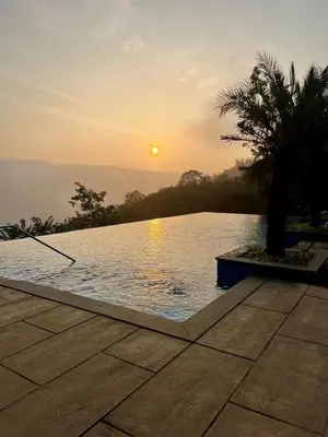 a pool with a palm tree next to a sunset at Silver Oak Resort Wayanad in Chithragiri