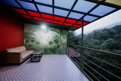 a balcony with a couch and a view of the mountains at Mayaahi Resorts & Spa in Nilambūr