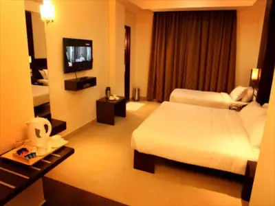 a hotel room with two beds and a television at Sunflower Hotel in Mysore