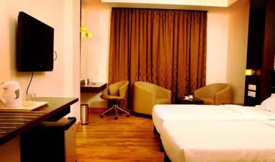 a hotel room with a bed and a desk and a television at Sunflower Hotel in Mysore