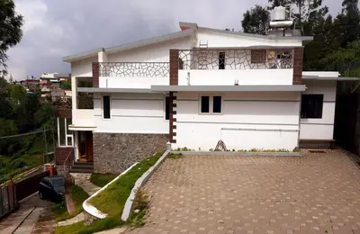 a white house with a balcony and a driveway at Greendale in Kotagiri