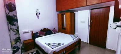 a small bedroom with a bed and a wooden door at The Bulbul Nest Homestay in Gūdalūr