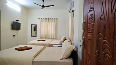 a hotel room with two beds and a door at Mahalakshmi Residency in Coimbatore