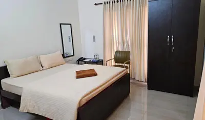 a bedroom with a bed and a chair in it at Mahalakshmi Residency in Coimbatore