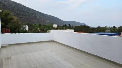 a balcony with a white fence and mountains in the background at Mahalakshmi Residency in Coimbatore