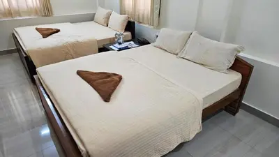 two beds in a hotel room withskirts at Mahalakshmi Residency in Coimbatore