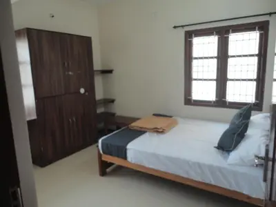 a bedroom with a bed and a dresser and a window at Sanvika Hotels & Service Apartments in Coimbatore