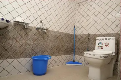 a bathroom with a toilet and a blue bucket at Lands End in Madikeri