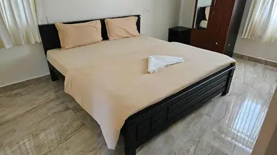 a large bed with a black frame and pillows at Mookambika Serviced Apartment in Coimbatore