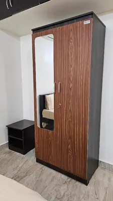 a wooden door in a bedroom with a mirror at Mookambika Serviced Apartment in Coimbatore