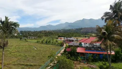 a resort with palm trees and mountains in the background at Marayoor home stay in Marayoor